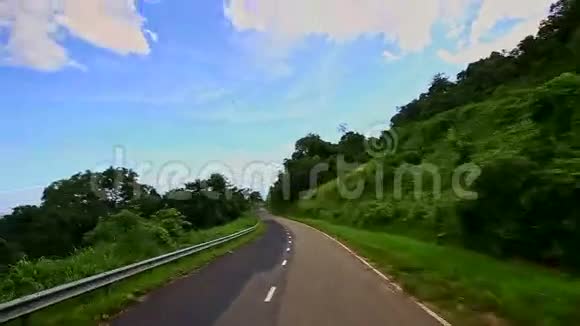 绿色植物景观间沿曲线乡村道路的运动视频的预览图