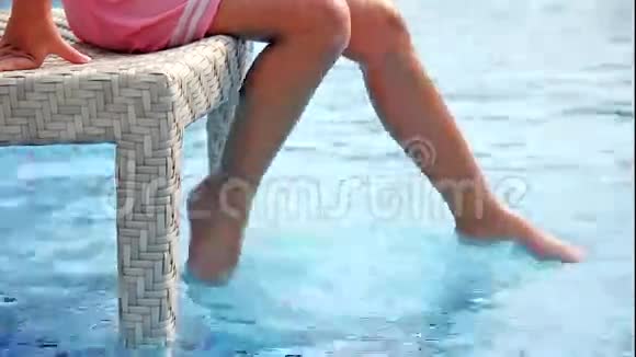 小女孩用腿泼水在游泳池附近玩得很开心视频的预览图