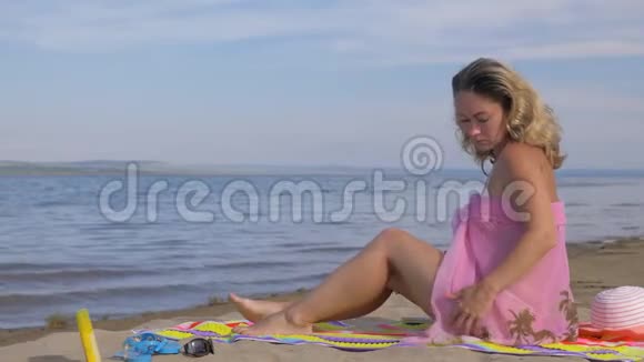 美丽的女人正在海滩上休息看着大海视频的预览图