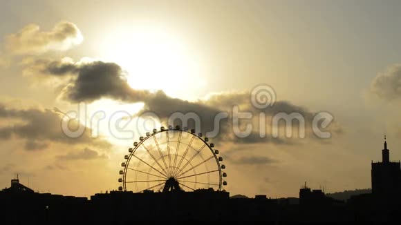 日落时摩天轮轮的轮廓在阴天时旋转视频的预览图