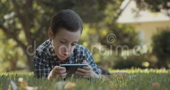 小男孩在户外草地上用手机视频的预览图