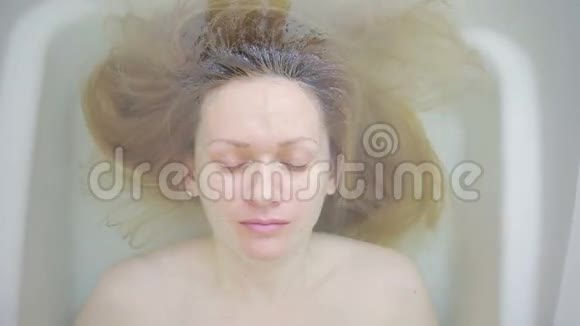 特写一个没有化妆的女人躺在浴缸里视频的预览图