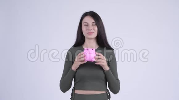 快乐的年轻漂亮的女人给猪存钱罐视频的预览图