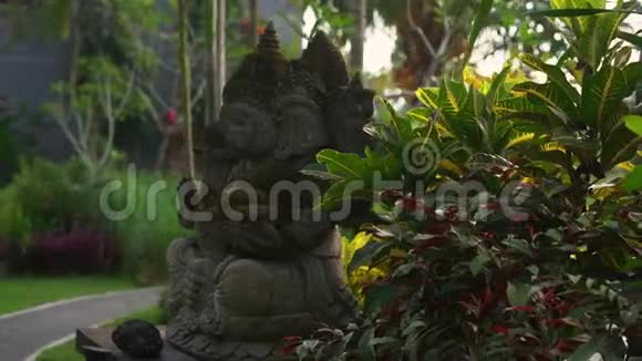 一个热带花园里长满苔藓的甘尼莎神的石像的慢动作稳定镜头视频的预览图