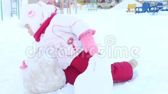 快乐的小女孩在冬天的晴天操场上玩雪视频的预览图