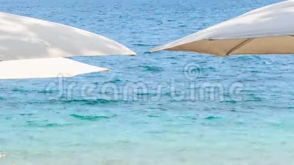 沙滩上蔚蓝的海面上的白色遮阳伞视频的预览图