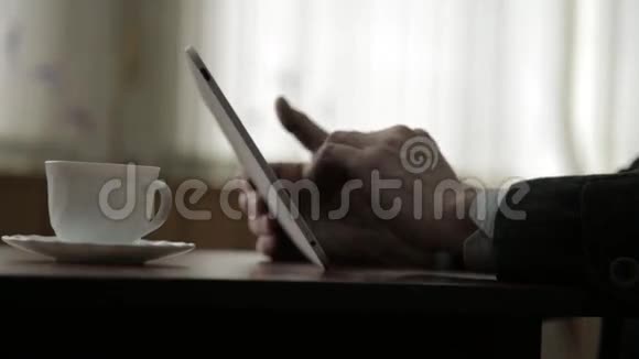 使用平板电脑和喝咖啡的人在窗户背景上特写双手视频的预览图