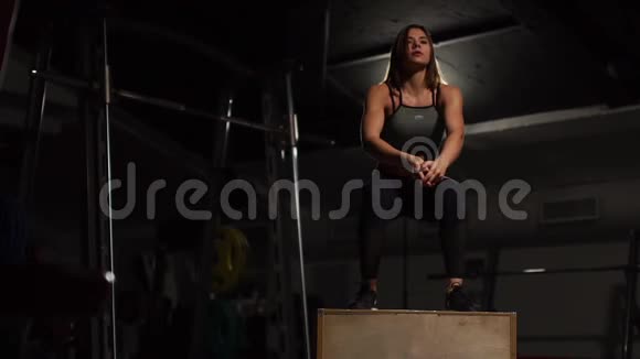 漂亮的女健身运动员穿着黑色的运动上衣和带脸的短紧身衣在黑暗的健身房里表演拳击视频的预览图