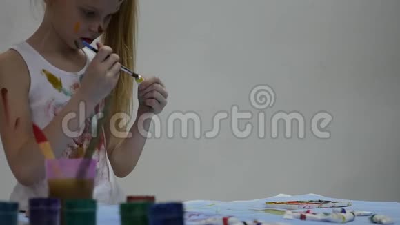 可爱的小女孩画家在桌子上画画在她的衣服上画画慢动作视频的预览图