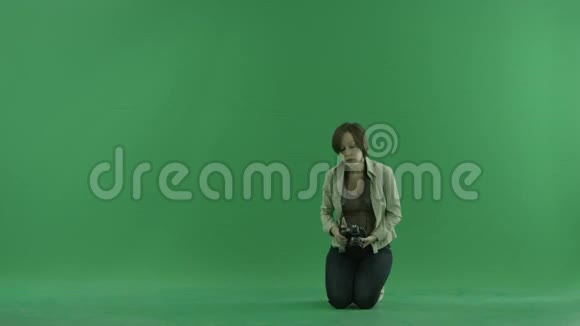 坐着的年轻女子正在绿色屏幕上拍摄宏观照片视频的预览图