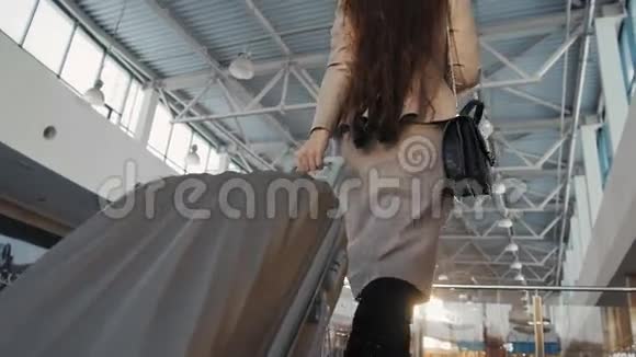 年轻的女乘客在机场带着她的平板电脑在候机楼等待她的航班视频的预览图