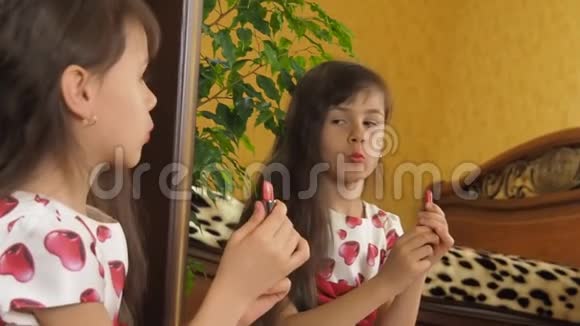 女孩画了她的嘴唇对着镜子涂口红的孩子带口红的小女孩视频的预览图