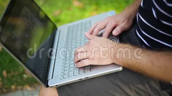 坐在公园长椅上的年轻人腿上放着笔记本电脑视频的预览图