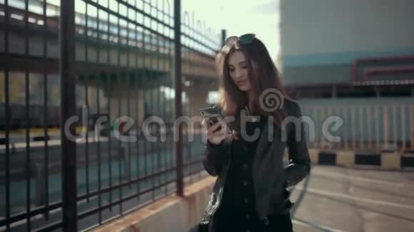 可爱的年轻黑发女人走路和使用智能手机视频的预览图