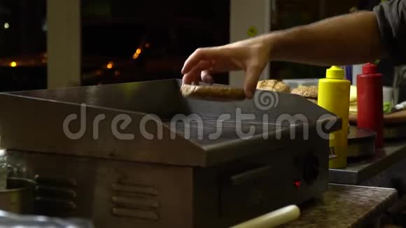 在开放式快餐厨房里做汉堡的过程厨师在炉子上烤面包晚上好视频的预览图