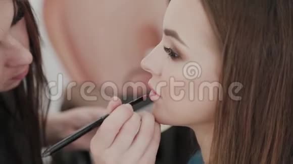 专业化妆师女士为美容院的客户画嘴唇视频的预览图
