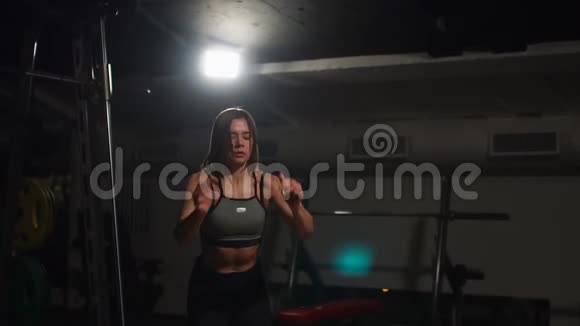 漂亮的女健身运动员穿着黑色的运动上衣和带脸的短紧身衣在黑暗的健身房里表演拳击视频的预览图