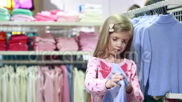 时尚的商店服装店里的小女孩选一套西装视频的预览图