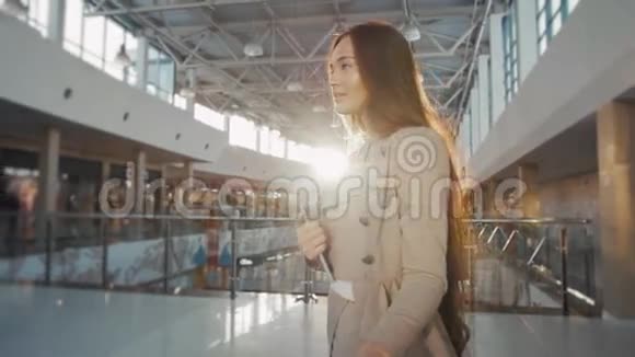 年轻的女乘客在机场带着她的平板电脑在候机楼等待她的航班视频的预览图