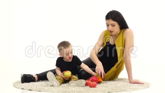 妈妈和孩子在宽敞的房间里看蔬菜白色背景视频的预览图