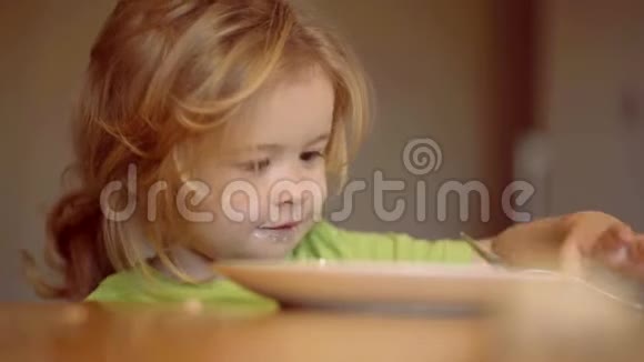 小男孩坐在桌子旁吃牛奶零食孩子吃东西孩子在家吃健康的食物年幼的孩子视频的预览图