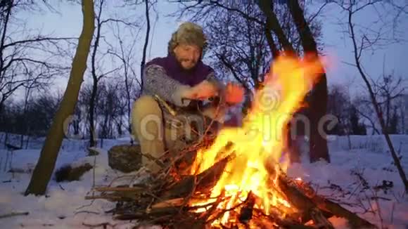 有胡子的人在冬天的炉火旁暖手游客晚上篝火视频的预览图