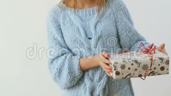 穿着毛衣的女孩与白色背景的圣诞礼物跳舞视频的预览图
