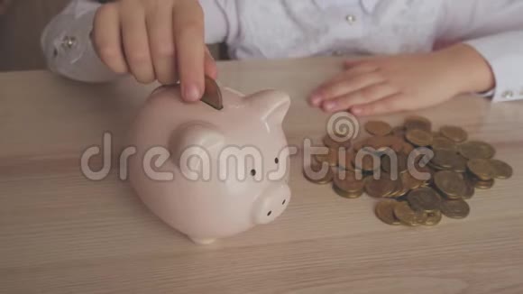 快乐的女孩把钱存到家里的储蓄罐里孩子将硬币插入储蓄罐室内金融概念孩子视频的预览图