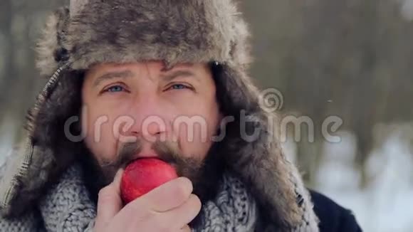 冬天有胡子的人拿苹果的肖像一个留胡子的年轻人在冬天吃苹果视频的预览图