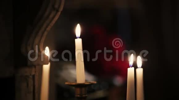 白蜡烛在燃烧开火背景上的红玫瑰花束火焰视频的预览图