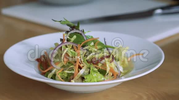 在盘子上倒入沙拉蔬菜的特写慢慢地视频的预览图