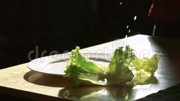 生菜沙拉在白色盘子上泼水滴在黑色背景上慢慢地视频的预览图