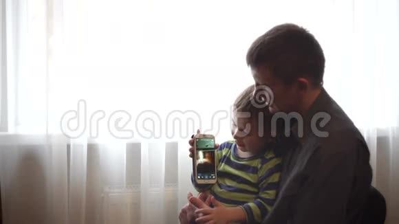 爸爸和儿子在智能手机上看图片和视频视频的预览图