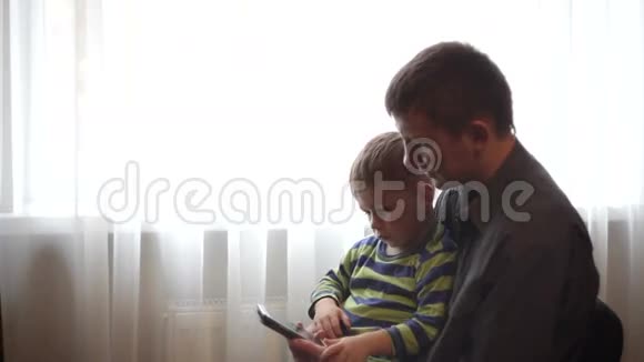 爸爸和儿子在智能手机上看图片和视频视频的预览图