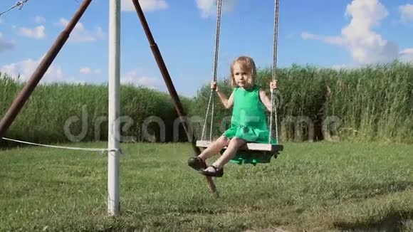 一个迷人的金发小女孩正在绿色的田野上摇摆视频的预览图