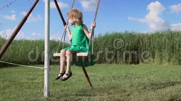 一个迷人的金发小女孩正在绿色的田野上摇摆视频的预览图
