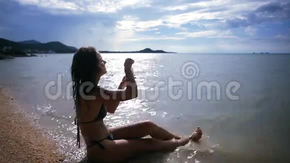 穿比基尼的女人坐在海边视频的预览图