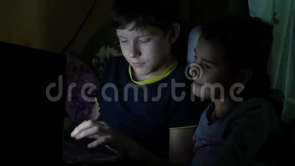 儿童男孩和女孩晚上在笔记本电脑上玩网络游戏视频的预览图