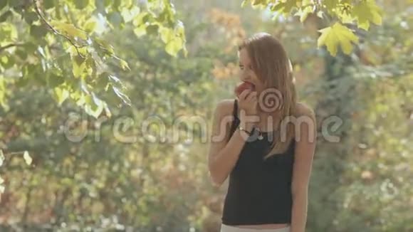 女孩在公园里吃了一口红苹果视频的预览图