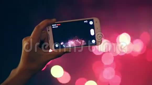 一个男人用手机拍摄五颜六色的焰火视频的预览图