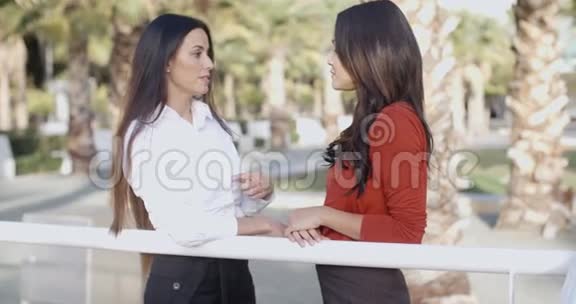 两位年轻的女士站着说话视频的预览图
