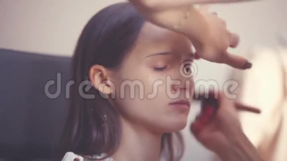 化妆师在一个重要的活动之前给一个年轻的女人化妆化妆用品1920x1080视频的预览图
