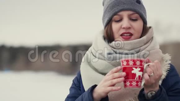 年轻女子在雪地的地平线上享受着早间咖啡或茶视频的预览图