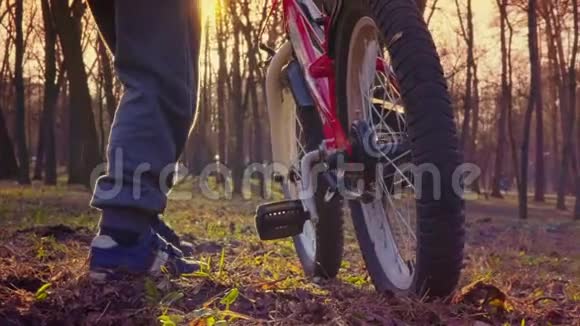 小男孩在公园里骑自行车日落公园慢动作视频的预览图
