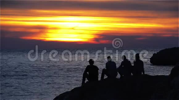 一群坐在岩石上享受日落的青少年视频的预览图