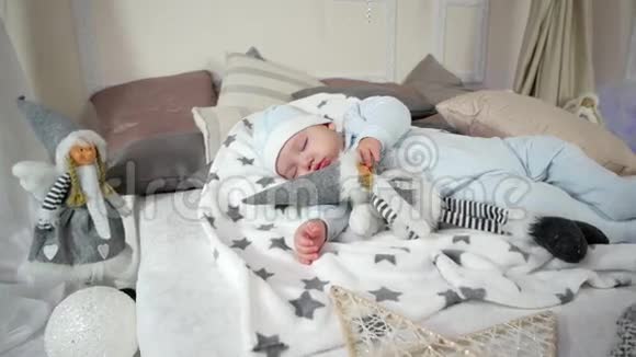 婴儿躺在床上的滑块和帽子甜蜜的梦中可爱的男孩孩子抱着玩具睡觉小孩子视频的预览图