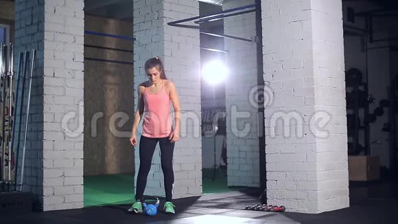 运动妇女在蹲姿时用壶铃锻炼视频的预览图
