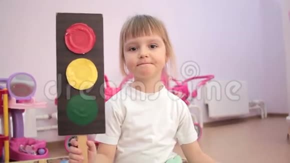 小女孩手里拿着玩具红绿灯坐着挥舞着手微笑着视频的预览图
