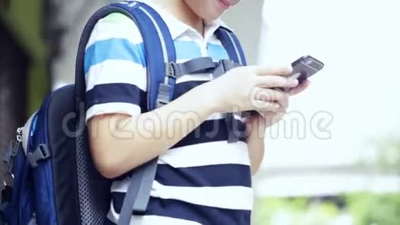 带背包的亚洲儿童使用数码手机视频的预览图
