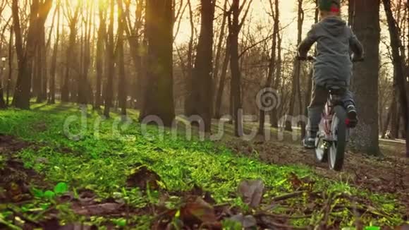 小男孩在公园里学骑自行车日落公园慢动作视频的预览图